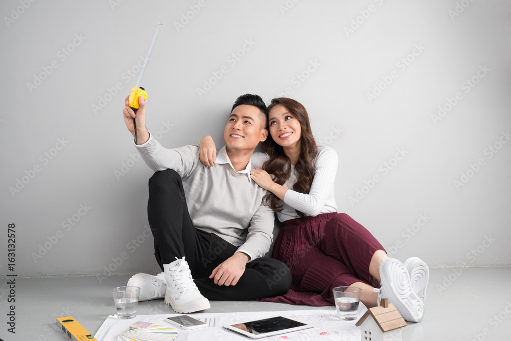 Young asian adult couple sitting on flor planning new home design.