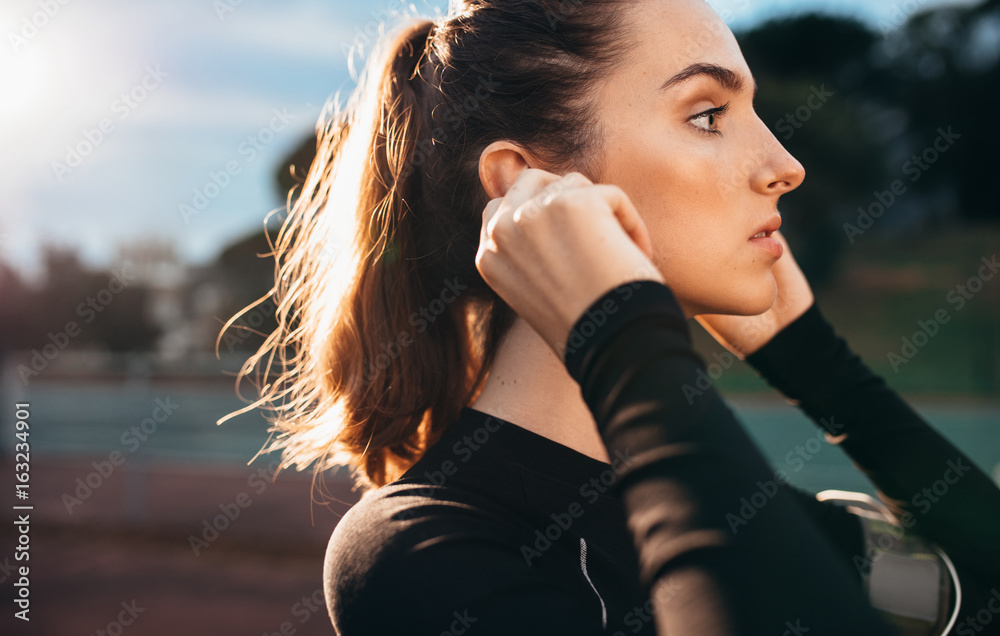 Beautiful sportswoman with earphones outdoors