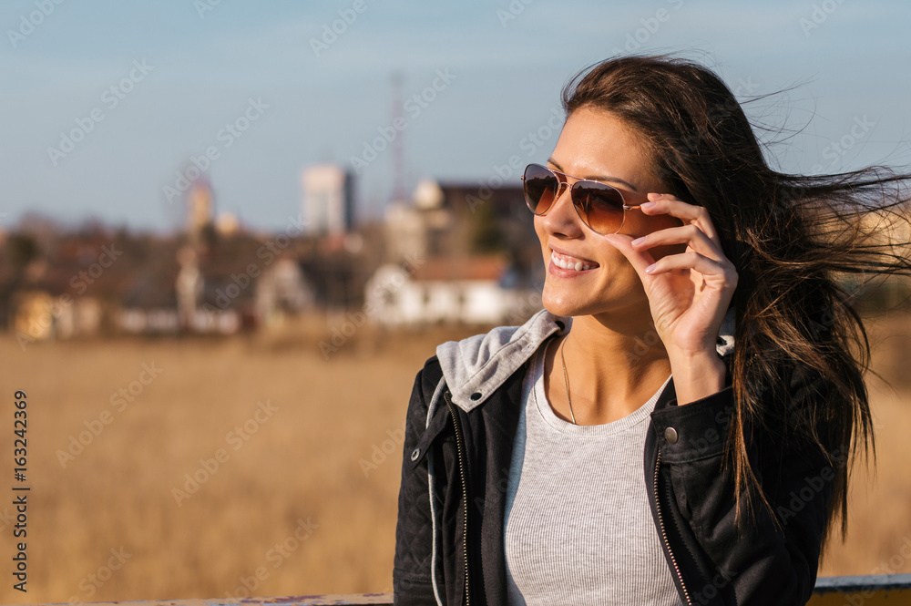 一个微笑的女人在户外戴着墨镜的肖像