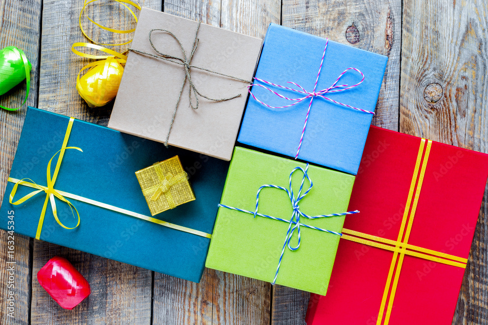 Colored gift boxes on wooden background with ribbon and straw