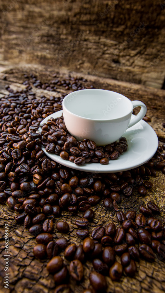 Coffee beans in a white mug. Coffee beans on a wooden background. Dark background.