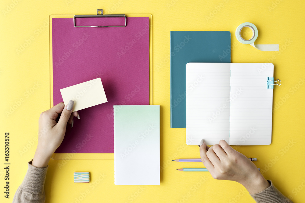 Hand Open Blank Notebook and Stationery on Yellow Background