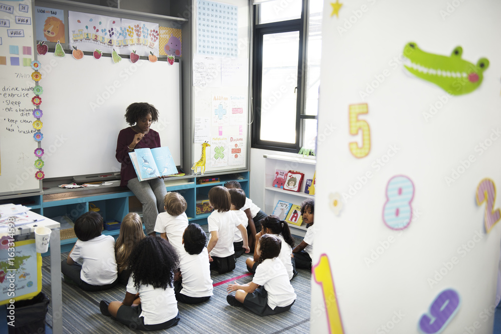 Kindergarten students sitting on the floor listening to story telling