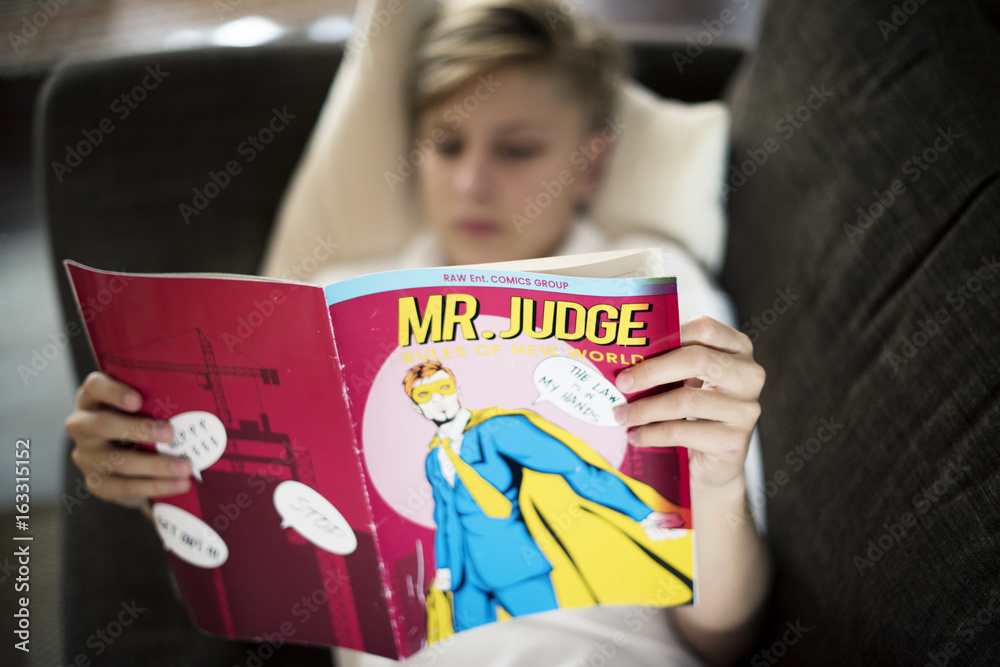 Young caucasian man lying on the couch reading cartoon