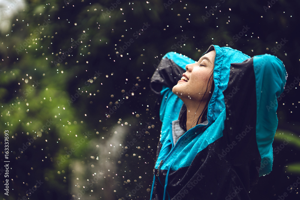 Asian woman wearing a raincoat outdoors. She is happy.