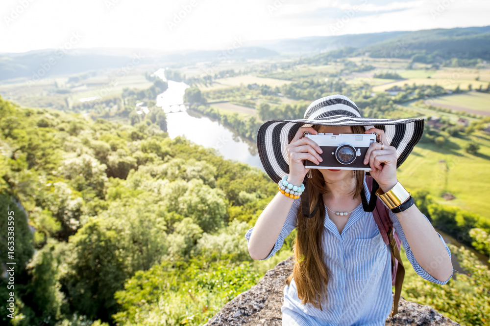 Young happy woman tourist with photo camera traveling near the Domme village in France