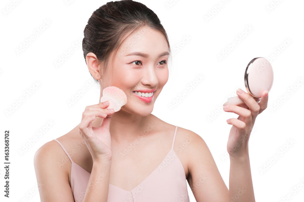 Portrait of beautiful young asian woman with perfect fresh clean skin applying cosmetic brush and us