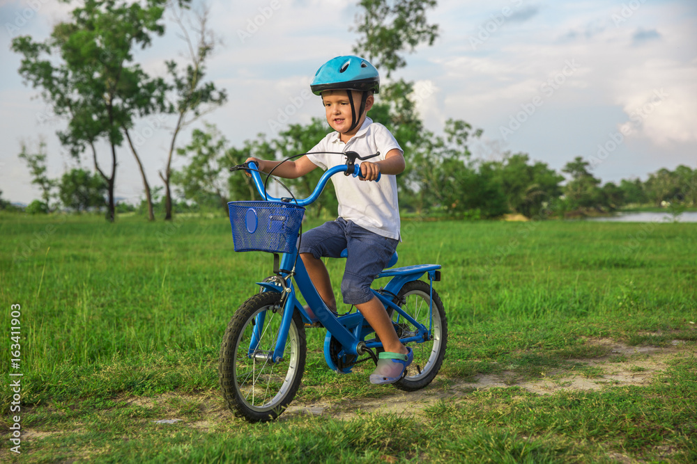 The child riding a bicycle. The kid in a helmet riding a bike in the park. Beautiful baby.