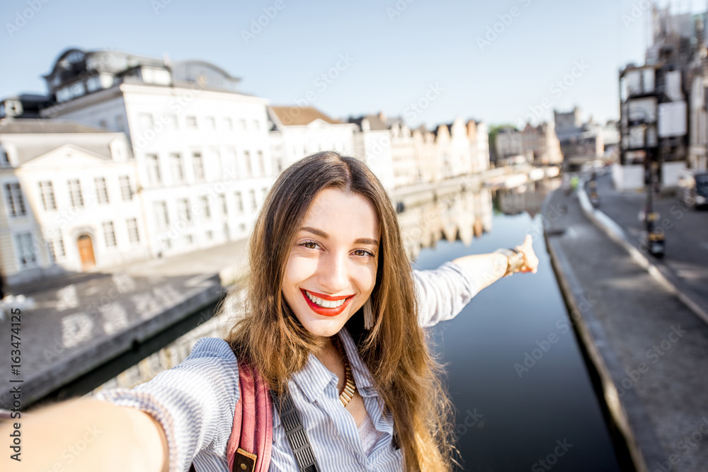 年轻的女游客站在桥上自拍，欣赏B根特市的美景