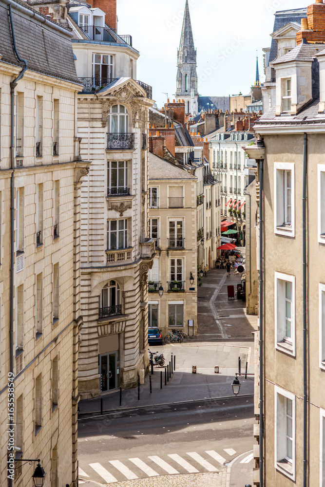 Street view on the beautiful residential buildings andchurch tower in Nantes city during the sunny d