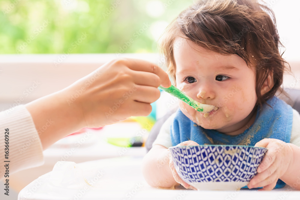 Happy little baby boy being fed by his mother