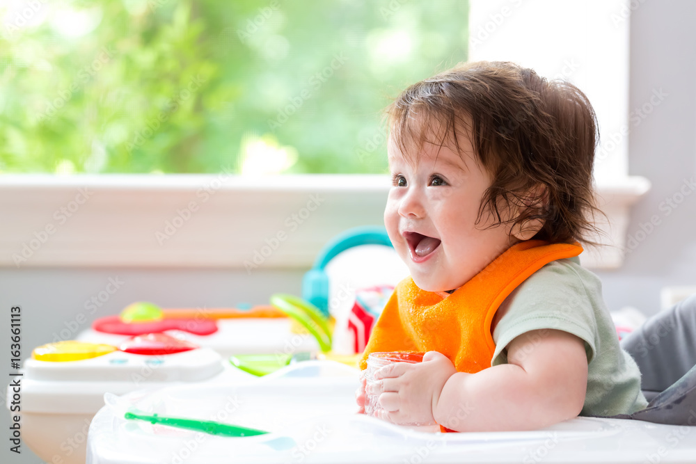 Happy little baby boy with a big smile eating food