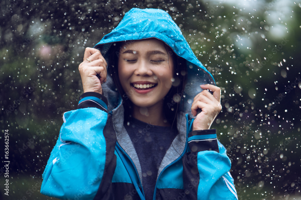 亚洲女人在户外穿着雨衣。她很开心。