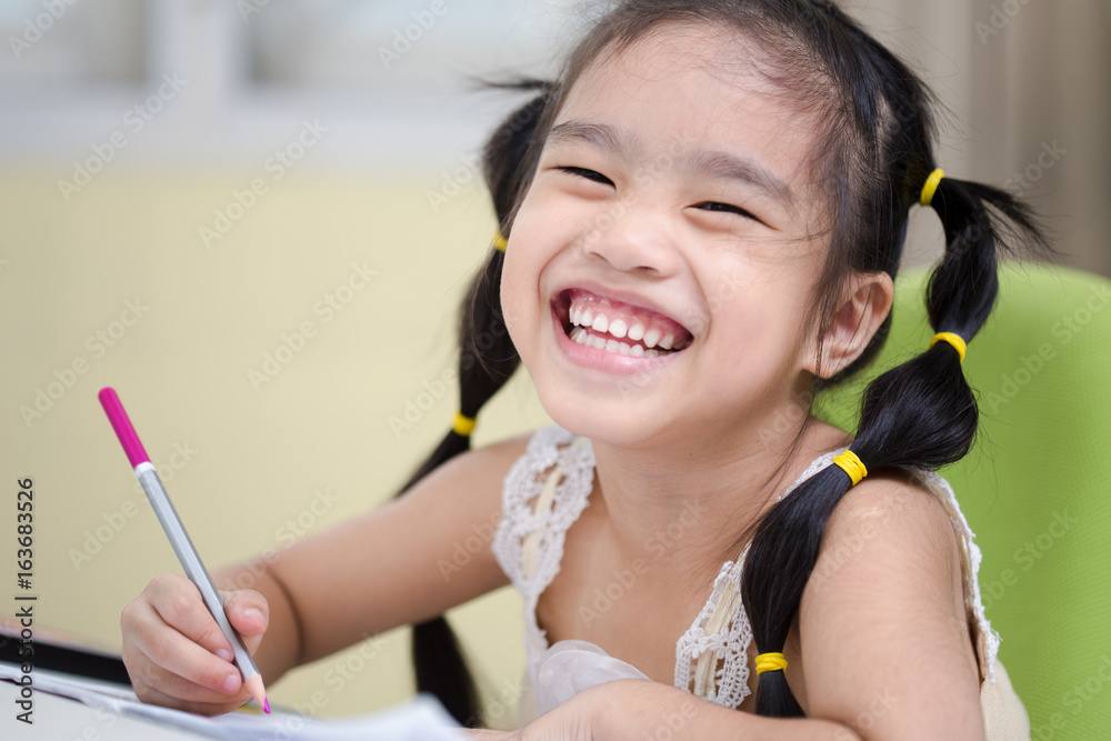 Cute little girl doing homework, reading a book,