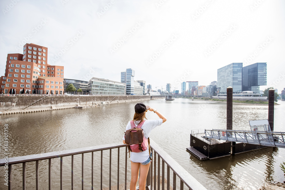 德国杜塞尔多夫市，一位年轻女子在港口欣赏现代建筑的美景