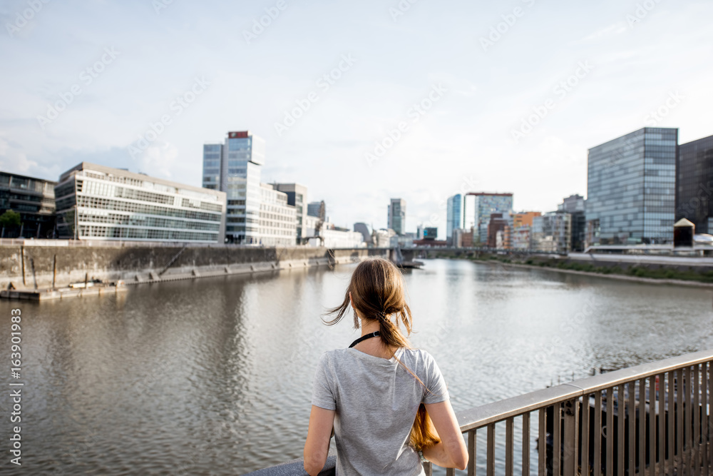 德国杜塞尔多夫市，一位年轻的女士在港口欣赏着现代建筑的美景