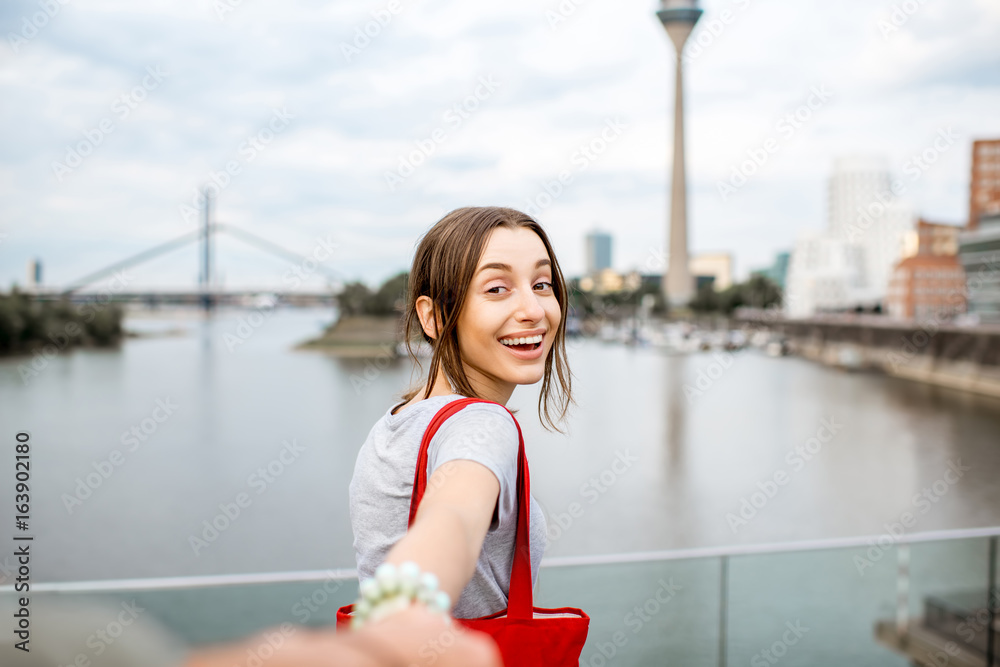 德国杜塞尔多夫现代城市背景下年轻快乐的女人牵手。关注我c