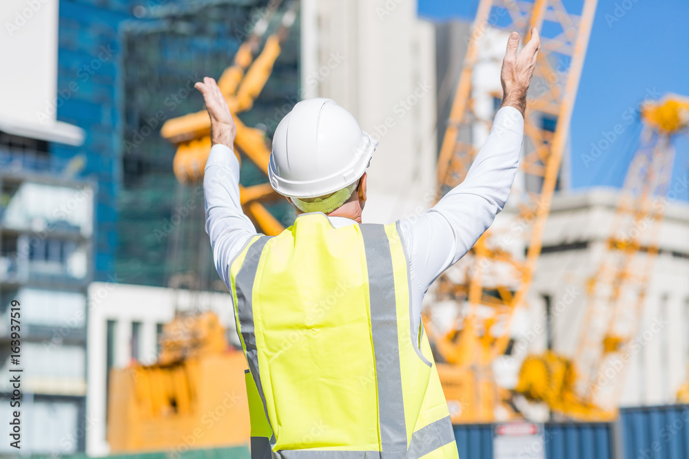 Senior foreman in glasses doing his job at building area on sunny day