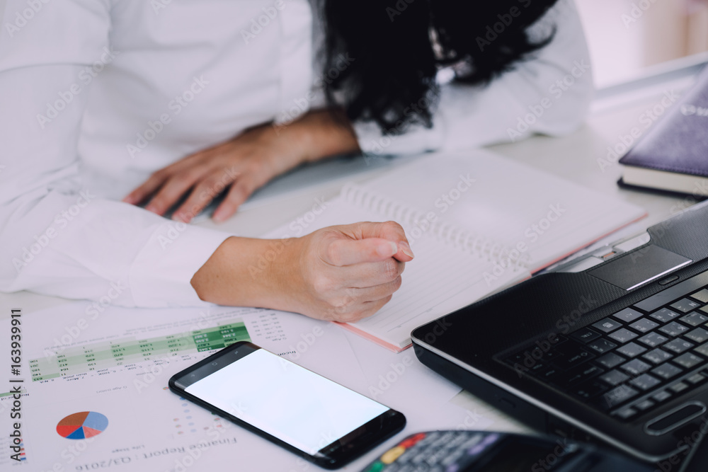 woman working in office interior on pc holding smartphone.Office person using mobile phone and lapto