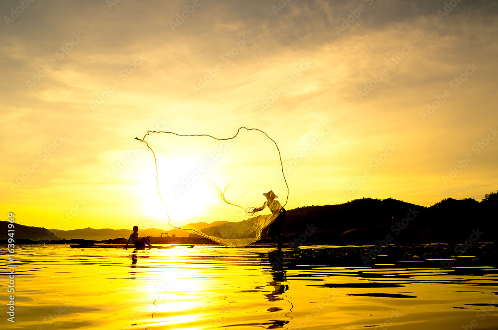 People fishing in river On the bright sky a beautiful golden color in Thailand.