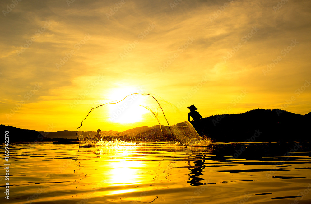 People fishing in river On the bright sky a beautiful golden color in Thailand.