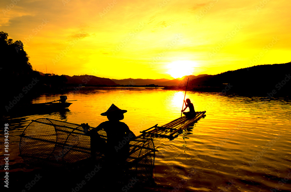 People fishing in river On the bright sky a beautiful golden color in Thailand.