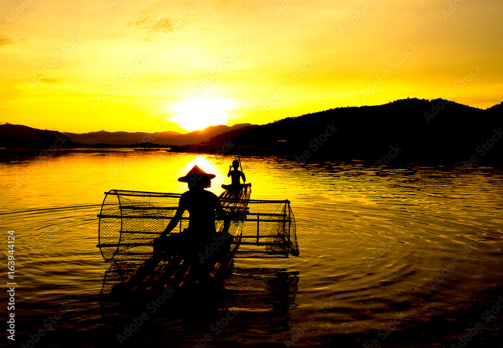 People fishing in river On the bright sky a beautiful golden color in Thailand.