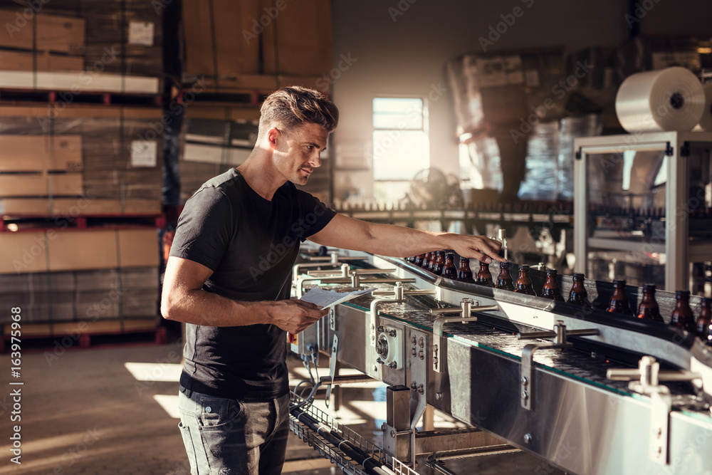 Young man supervising the beer production at brewery