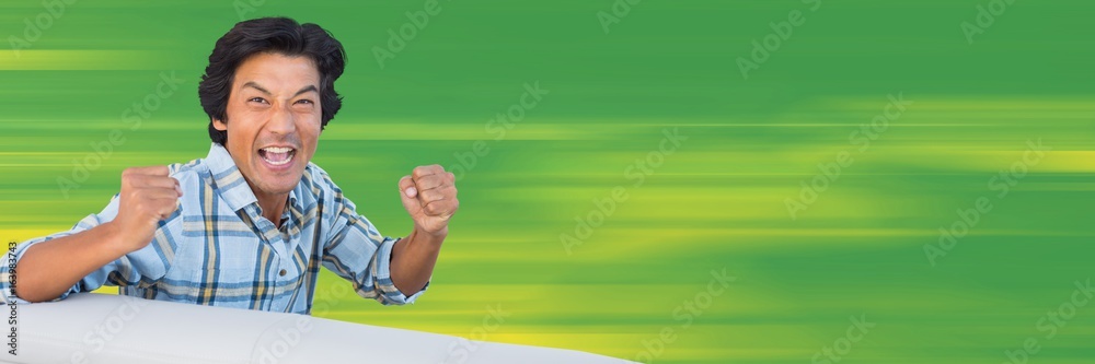 Man cheering at table against blurry green background