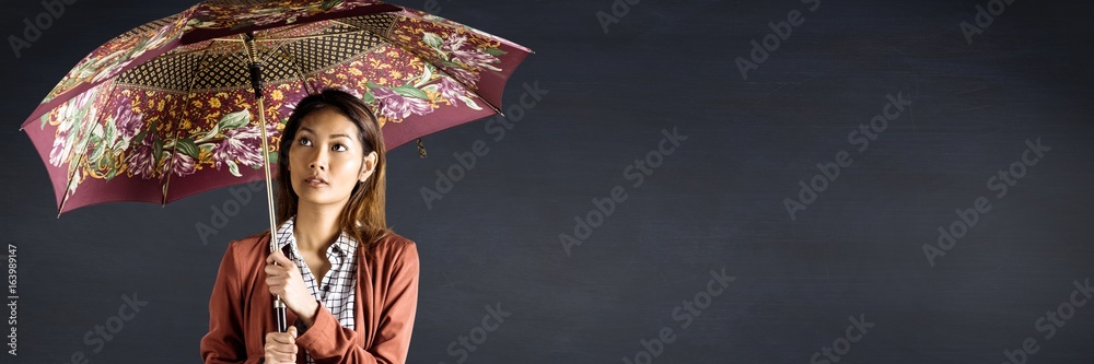 带图案雨伞的千禧一代女性靠着海军黑板