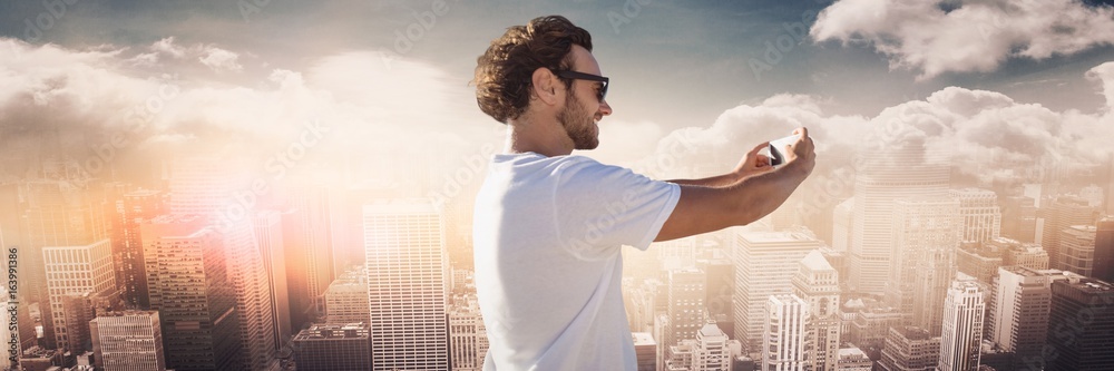 Man white shirt taking selfie against skyline with clouds