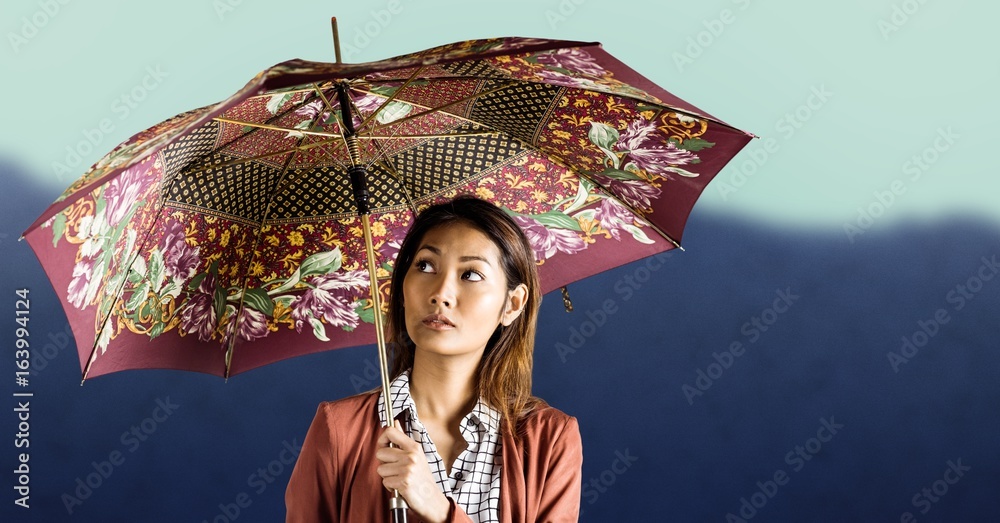 带图案雨伞的千禧一代女性，背靠模糊的山