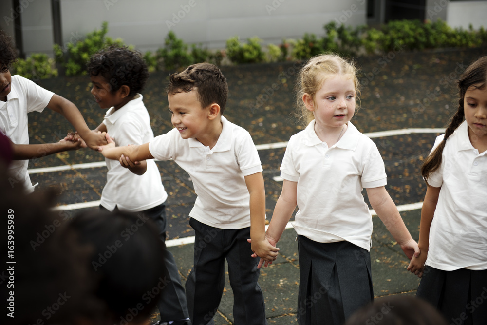 一群不同的幼儿园学生手牵手站在一起