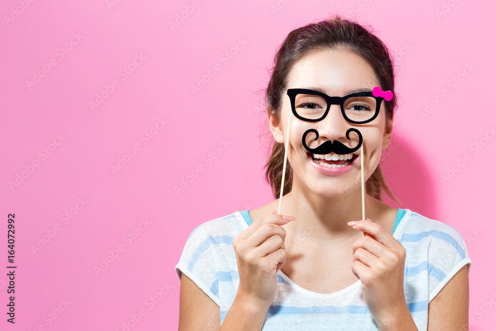 Young woman holding paper party sticks on a solid color background