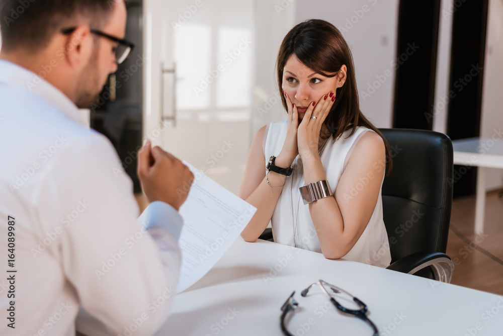 Young stressed female patient consulting with doctor.