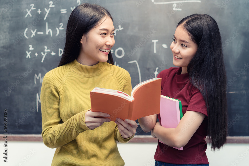 亚洲女学生在大学课堂上举着黑板一起看书。Ed