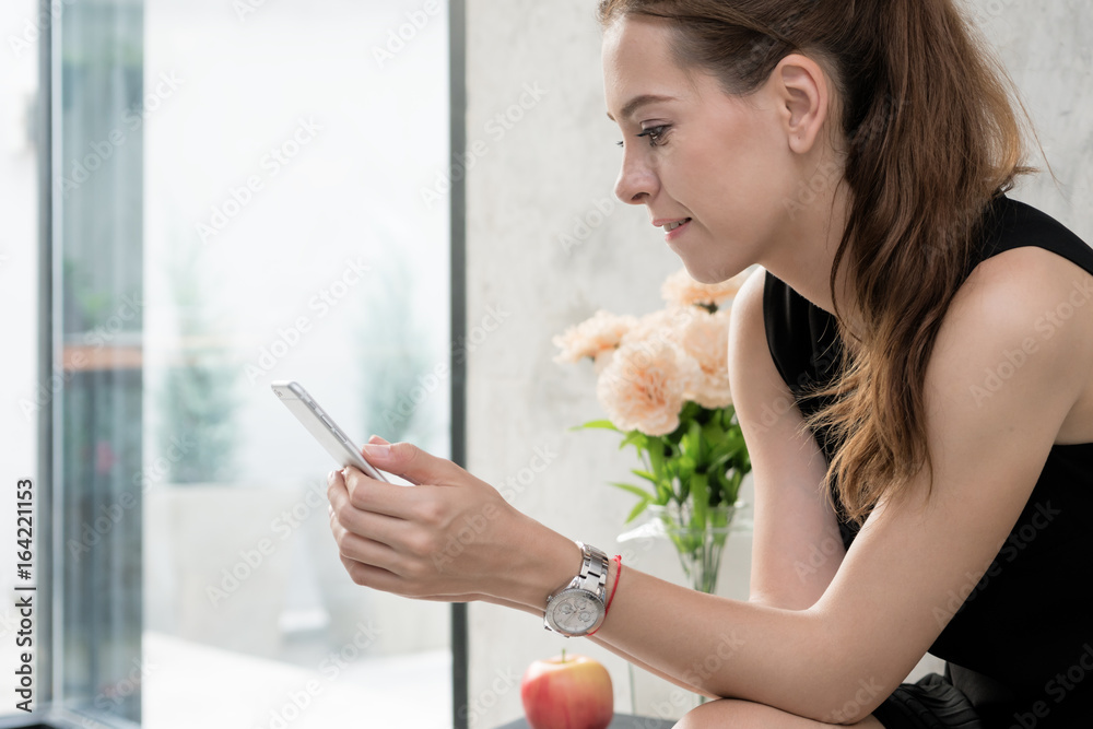 快乐的年轻女人拿着手机坐在家里的沙发上的肖像