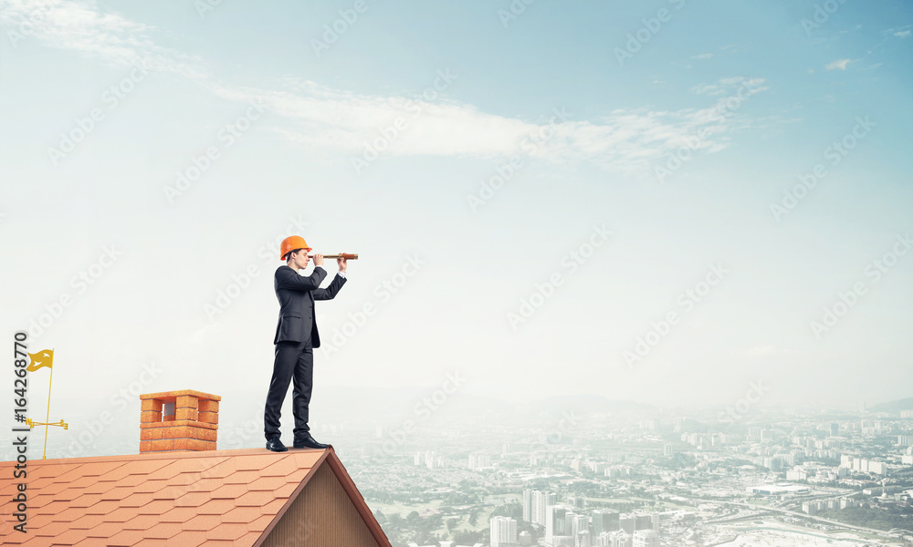 Engineer man standing on roof and looking in spyglass. Mixed med