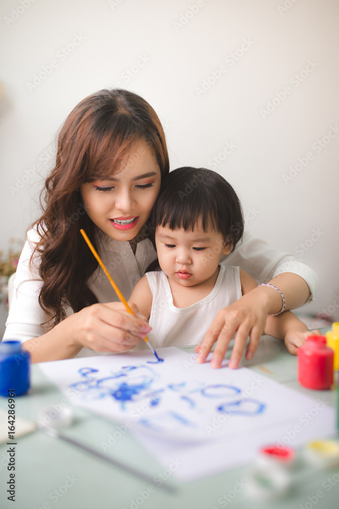 幸福的家庭，母亲和女儿一起画画。亚洲妇女帮助她的小女儿。