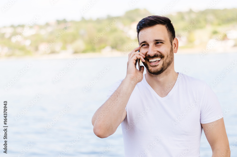 Handsome man with mobile phone outdoors.