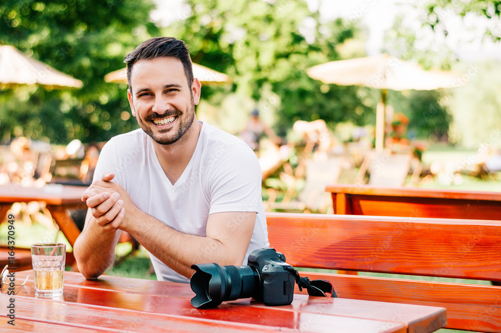 Portrait of young photographer sitting in street cafe.