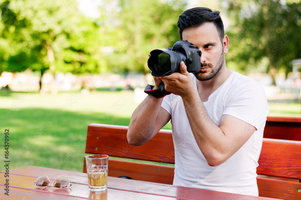 Happy male tourist taking photos at the cafe.