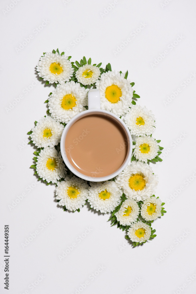 Flat lay of green leaves and flowers pattern with cup of coffee on white background