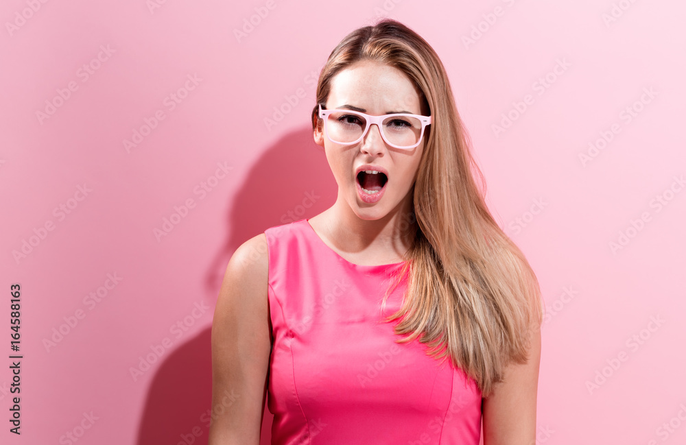 Unhappy young woman on a pink background