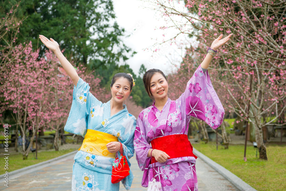 Two women open arms with cherry-blossom