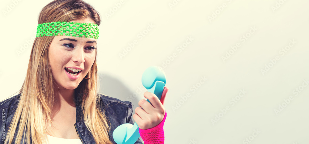 Woman in 1980s fashion with old fashioned phone on a white background