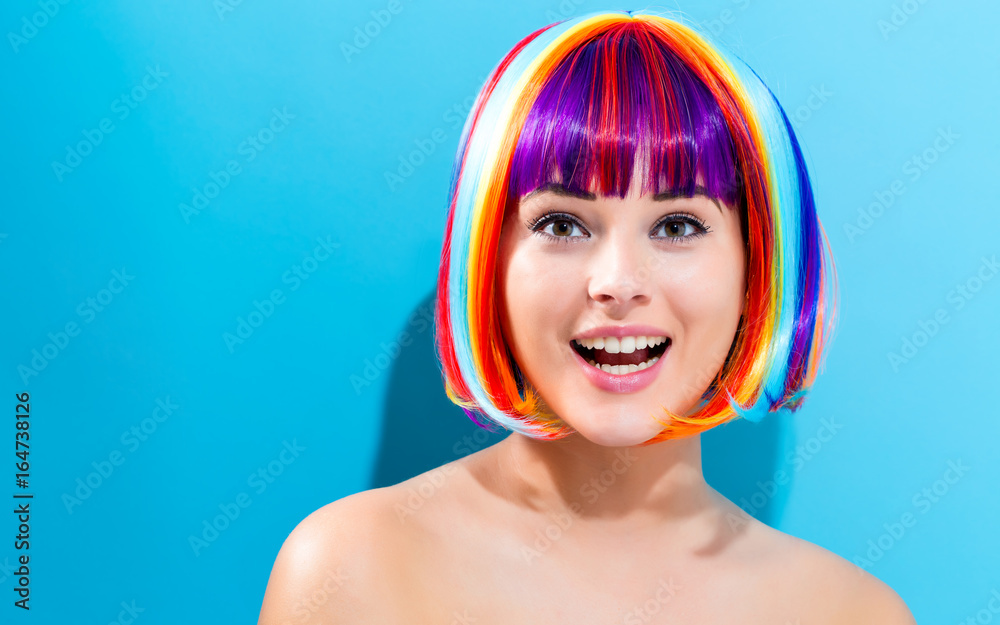 Beautiful woman in a colorful wig on a blue background