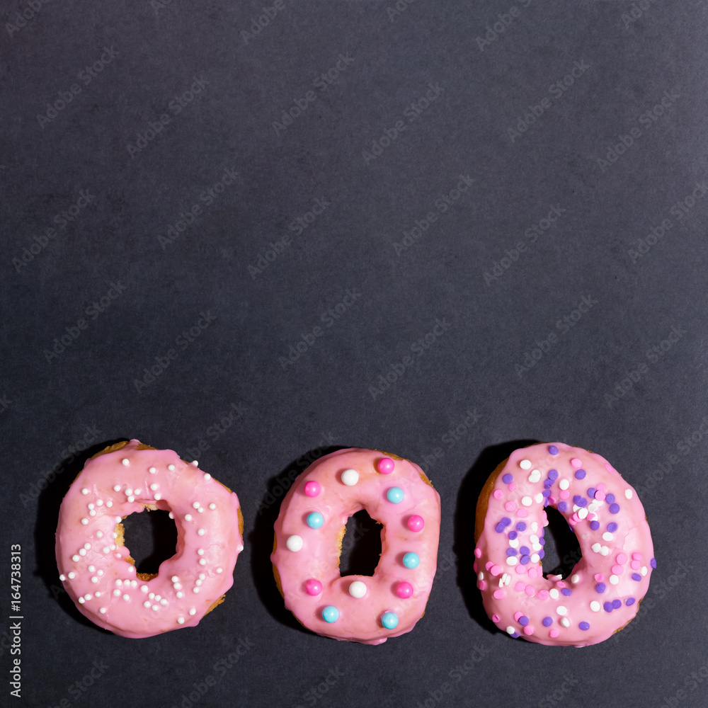 Colorful glazed donuts on a chalky black background