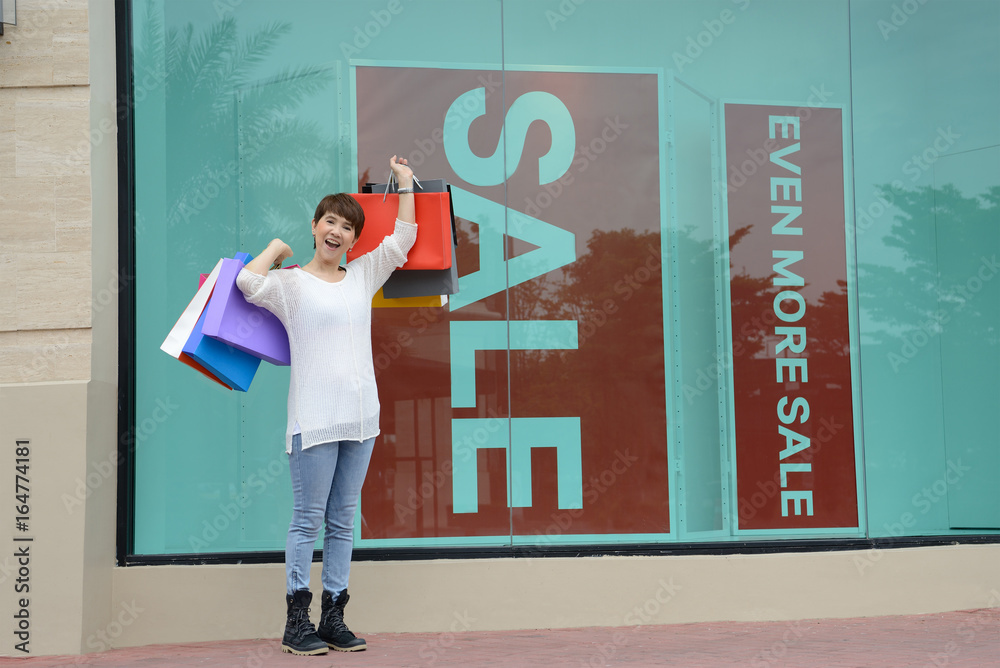 Happy woman at the mall holding shopping bags and smiling