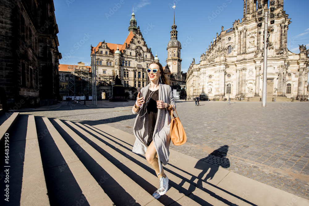 Lifestyle portrait of young businesswoman walking with bag at the old town of Dresden during the mor